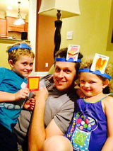 Man with 2 young kids playing a game with cards on their head
