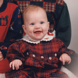 Smiling toddler in Christmas plaid outfit.
