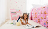 Girl laying on floor of bedroom decorated with Horses bedding and a pink sling bookshelf.