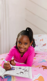 Girl with coloring book, laying on a bed with Horses bedding