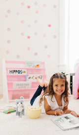 Girl laying on floor of bedroom decorated with Horses bedding and a pink sling bookshelf.