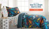 Kids dinosaur bed-in-a-bag bedding set styled on a bed in a bright bedroom with on-image text “Reset & Refresh: Gear for a Bright Start to 2026” and a “Shop Bedding” button.