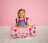 Young girl sitting on floor with strawberry patch toddler nap mat wearing a matching backpack