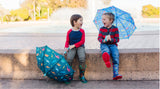 Two boys laughing outside while holding Jurassic Dinosaurs and Heroes Kids Umbrellas