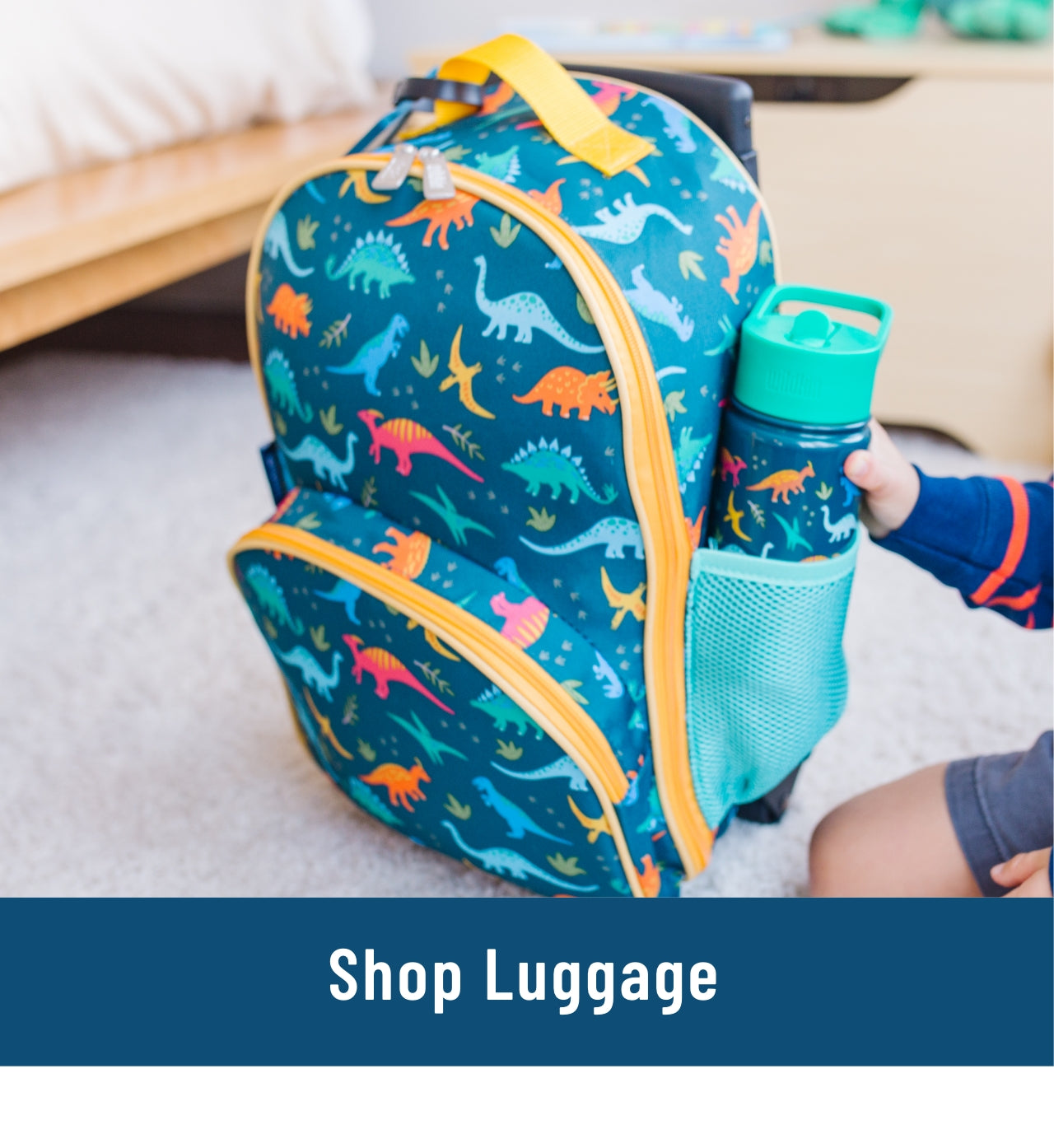 Image of dinosaur rolling luggage with a matching water bottle in the side mesh pocket. Link to shop Luggage.