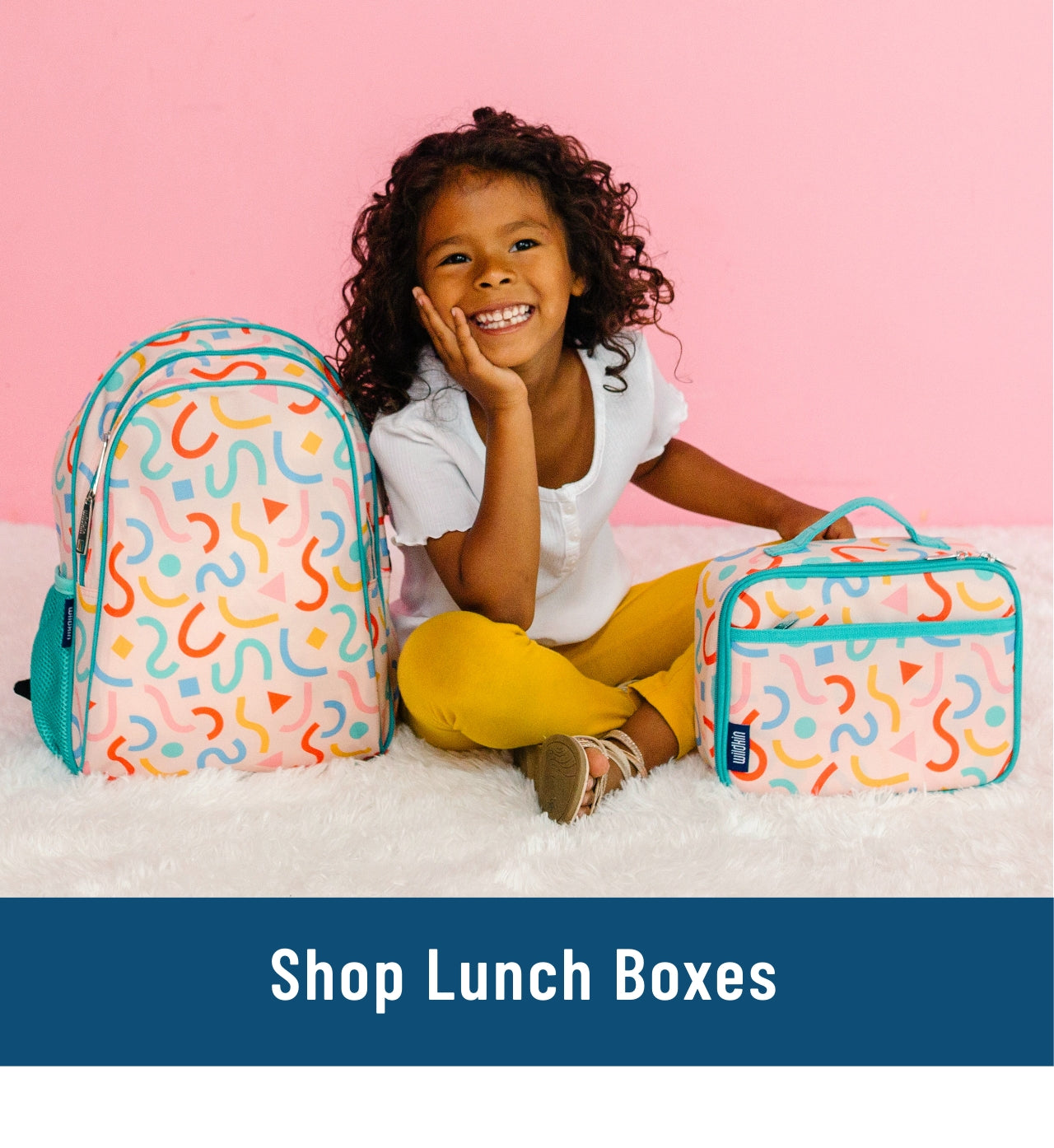 Link to shop lunch boxes. Image of girl sitting on floor with confetti peach backpack and lunch box.