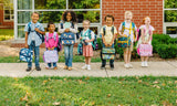 Group of kids standing outside a school holing items from the Wildkin Next Gen Eco School Gear Collection