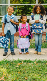 Group of kids standing outside a school holing items from the Wildkin Next Gen Eco School Gear Collection