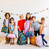 Group of children standing together indoors holding backpacks and lunch bags in different Wildkin patterns.